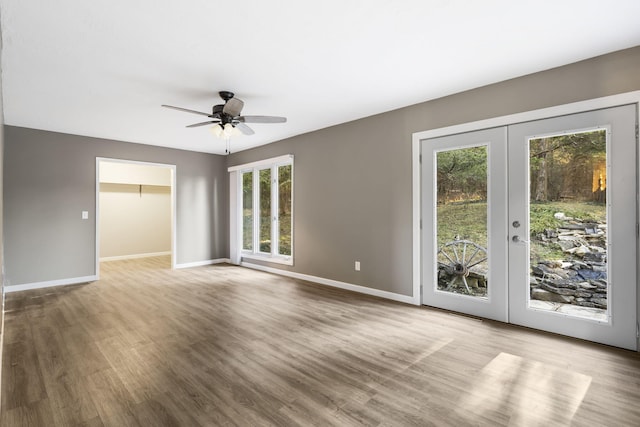 unfurnished living room with a ceiling fan, baseboards, wood finished floors, and french doors