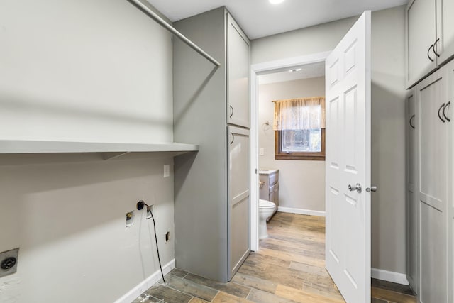 laundry area with light wood-style flooring, cabinet space, electric dryer hookup, and baseboards