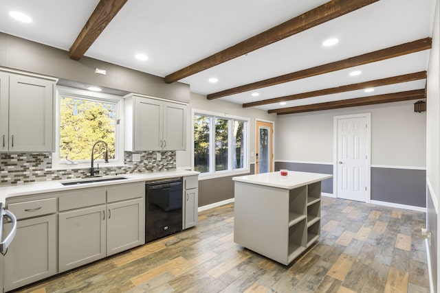 kitchen featuring a center island, a wainscoted wall, light wood-style flooring, a sink, and dishwasher