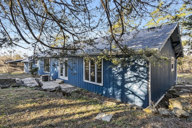 view of side of home with entry steps, french doors, a shingled roof, and central air condition unit