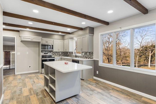 kitchen with gray cabinets, a center island, decorative backsplash, light wood-type flooring, and stainless steel appliances