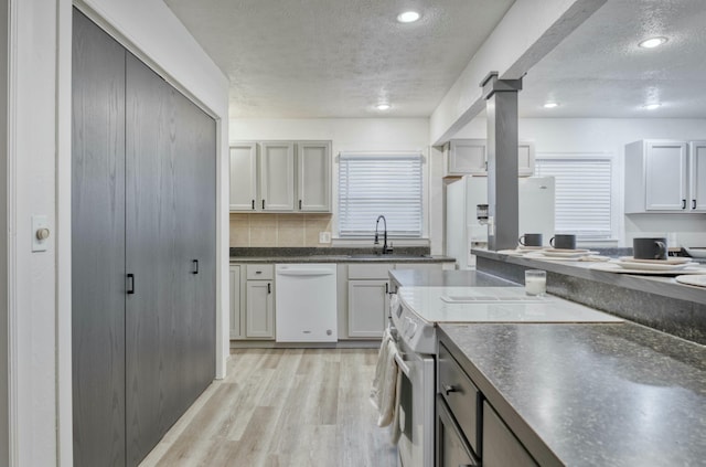 kitchen featuring a textured ceiling, white appliances, sink, gray cabinets, and light hardwood / wood-style floors