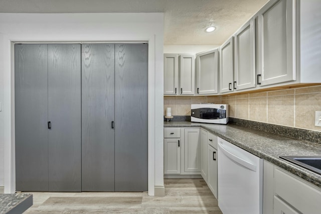 kitchen featuring decorative backsplash, a textured ceiling, white appliances, and light hardwood / wood-style flooring