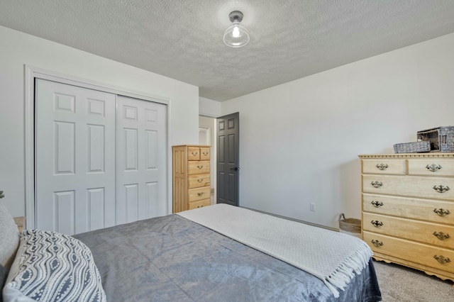 carpeted bedroom with a closet and a textured ceiling