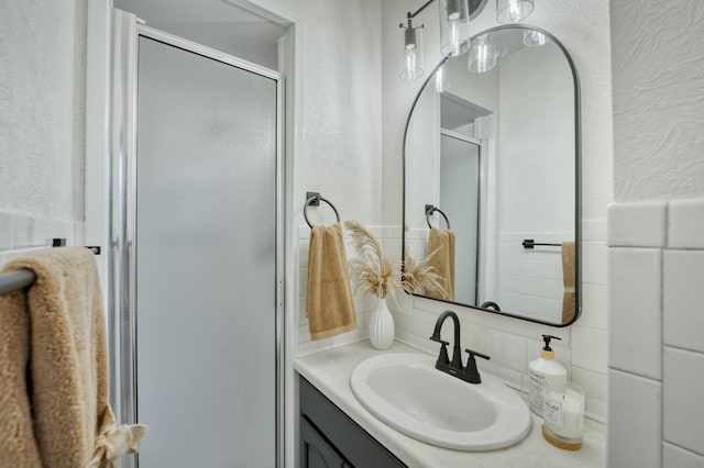 bathroom featuring vanity, tasteful backsplash, and a shower with door