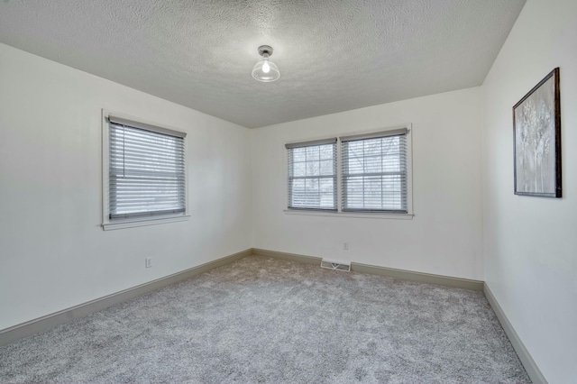 carpeted empty room featuring a textured ceiling