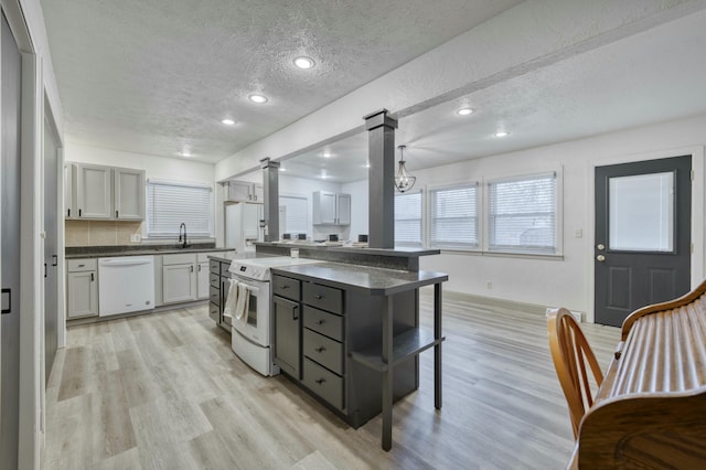 kitchen with a textured ceiling, gray cabinets, light hardwood / wood-style floors, and white appliances