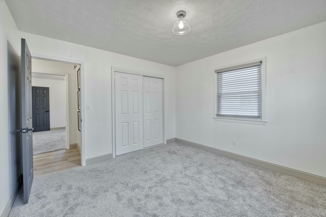 unfurnished bedroom with a textured ceiling, light colored carpet, and a closet