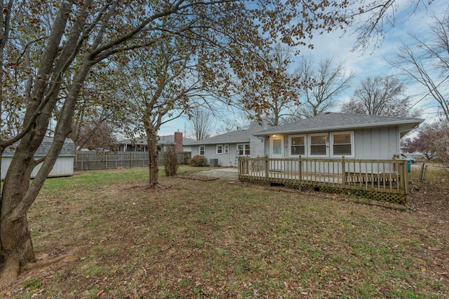 back of house featuring a wooden deck, a yard, and a storage unit