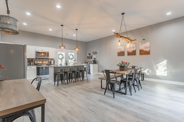 dining room with french doors and light hardwood / wood-style flooring