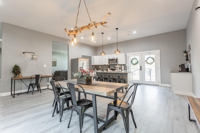 dining area with a chandelier, french doors, and light hardwood / wood-style flooring