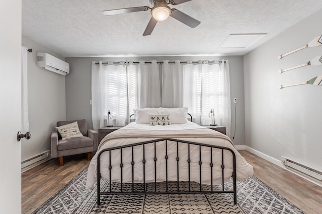 bedroom featuring ceiling fan, wood-type flooring, a baseboard radiator, and a wall mounted AC