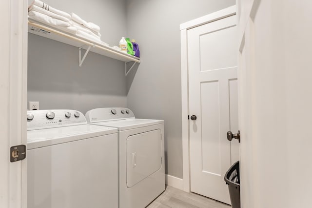 washroom with light hardwood / wood-style floors and washer and clothes dryer