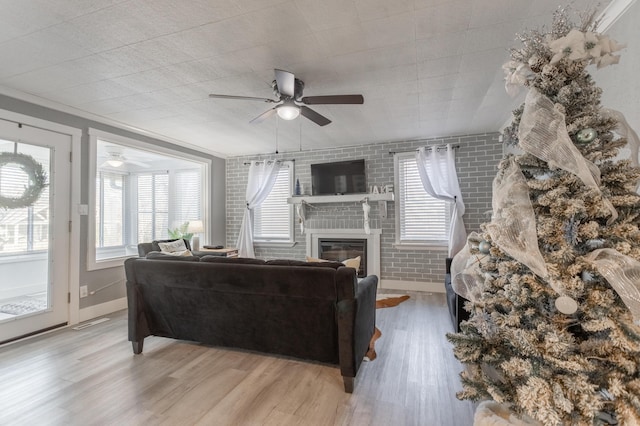 living room featuring a fireplace, brick wall, and light wood-type flooring