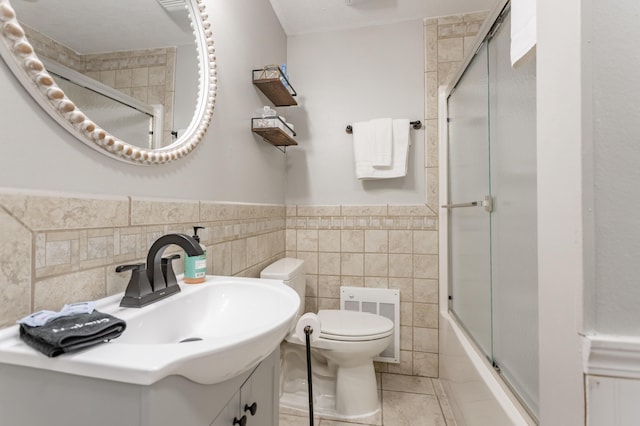 full bathroom with tile patterned flooring, combined bath / shower with glass door, toilet, vanity, and tile walls