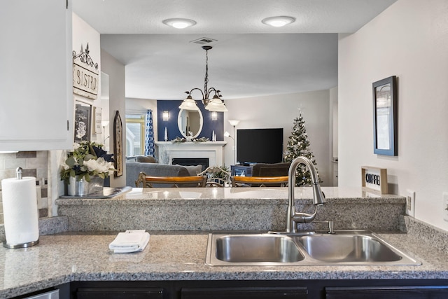 kitchen with sink, hanging light fixtures, a chandelier, a textured ceiling, and decorative backsplash