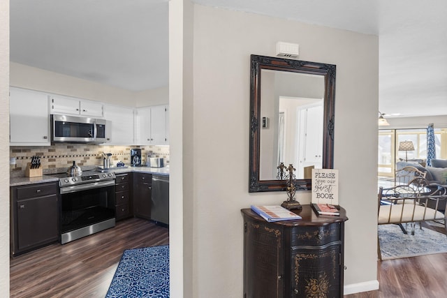 kitchen featuring backsplash, white cabinetry, dark hardwood / wood-style floors, and appliances with stainless steel finishes