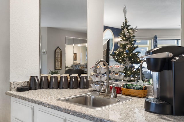 kitchen featuring white cabinetry, sink, and light stone countertops