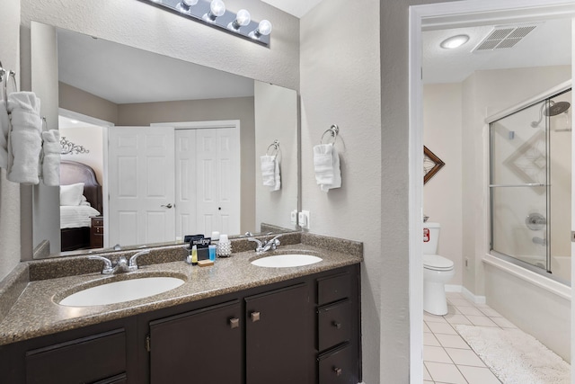 full bathroom with shower / bath combination with glass door, tile patterned flooring, vanity, and toilet