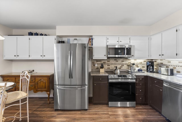 kitchen featuring white cabinets, appliances with stainless steel finishes, light stone counters, and dark wood-type flooring