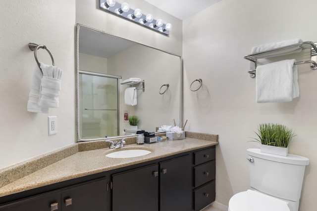 bathroom featuring vanity, toilet, and a shower with door