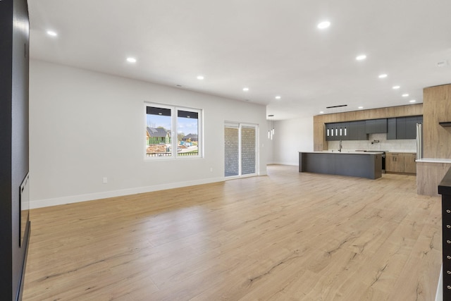 252 Hickory Hills Blvd, Springfield, MO 65802 - unfurnished living room featuring recessed lighting, light wood-type flooring, baseboards, and a sink