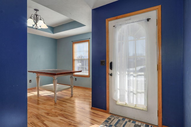 foyer with a chandelier, light hardwood / wood-style floors, and a tray ceiling