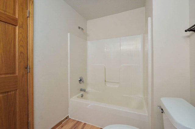 bathroom featuring hardwood / wood-style flooring, toilet, and bathing tub / shower combination