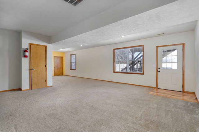 basement featuring light colored carpet and a textured ceiling