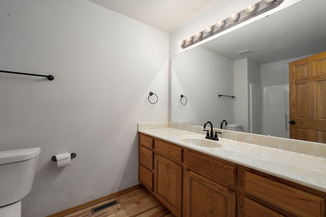 bathroom featuring a shower, hardwood / wood-style floors, vanity, and toilet