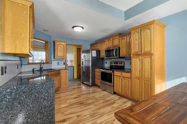 kitchen with decorative backsplash, appliances with stainless steel finishes, dark stone countertops, and sink