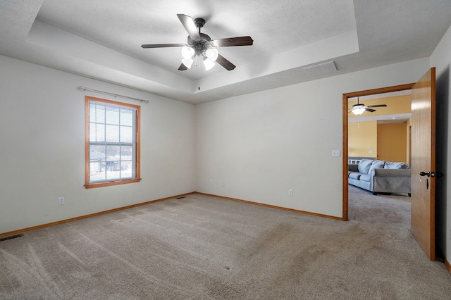 carpeted empty room with a tray ceiling and ceiling fan