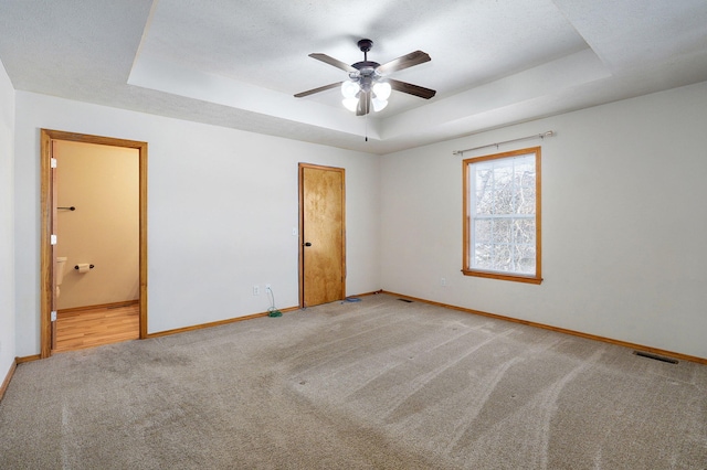 spare room featuring carpet flooring, ceiling fan, and a raised ceiling