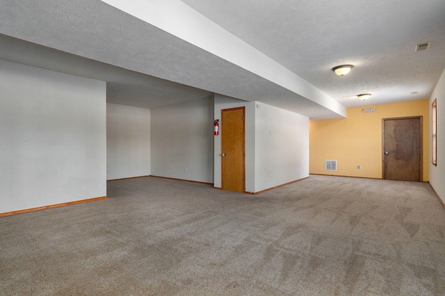 basement featuring light colored carpet and a textured ceiling