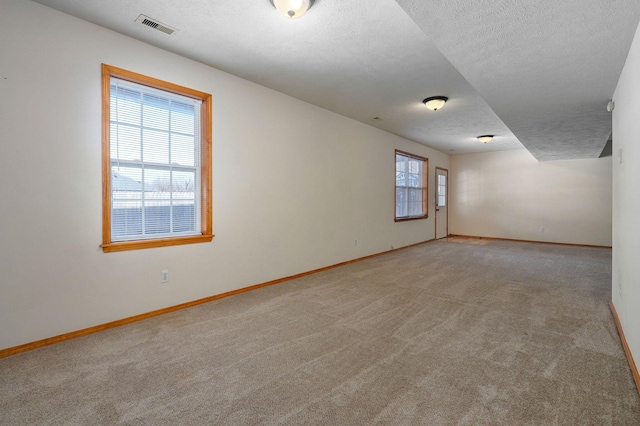 spare room featuring a textured ceiling and light carpet