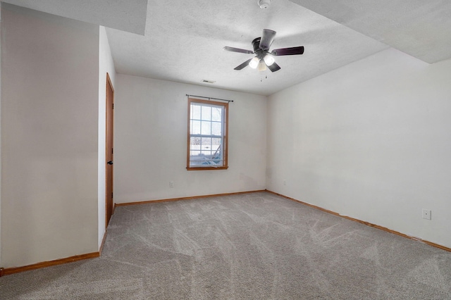 unfurnished room featuring ceiling fan, light colored carpet, and a textured ceiling