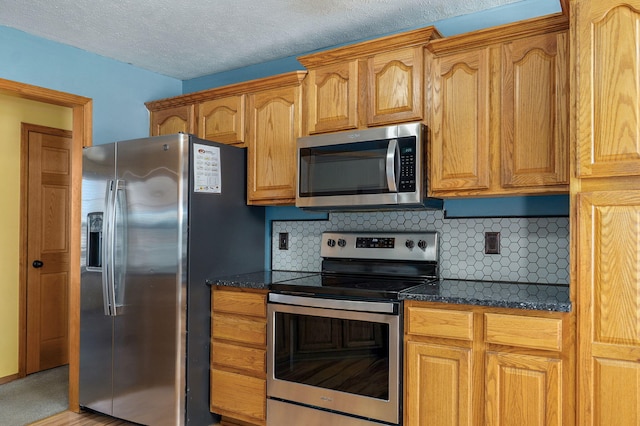 kitchen with decorative backsplash, dark stone counters, a textured ceiling, and appliances with stainless steel finishes