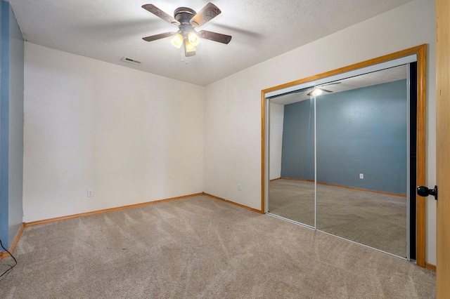 unfurnished bedroom featuring ceiling fan, a closet, carpet floors, and a textured ceiling