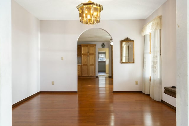 interior space featuring wood finished floors, arched walkways, and baseboards