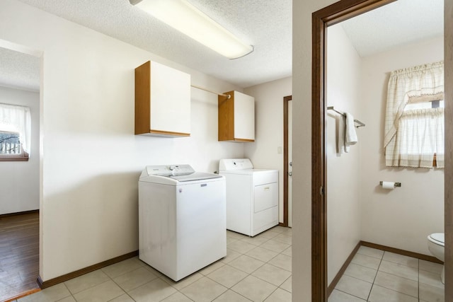 washroom with light tile patterned floors, baseboards, laundry area, a textured ceiling, and washer and clothes dryer