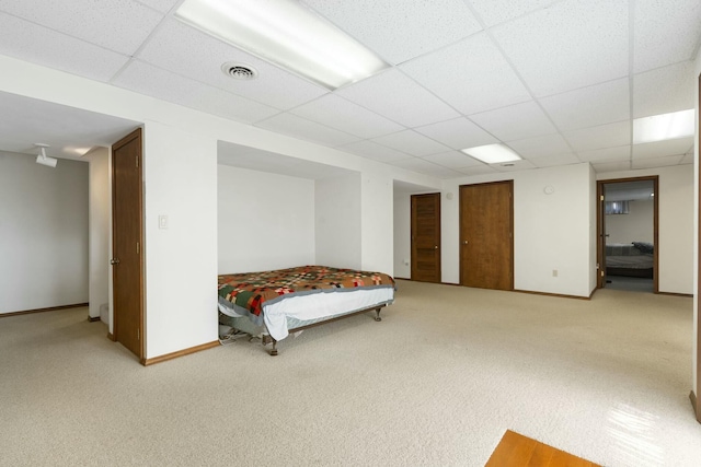 unfurnished bedroom featuring carpet flooring, visible vents, baseboards, and a drop ceiling