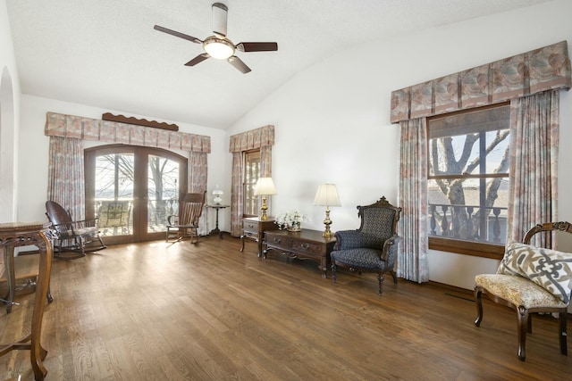 sitting room with french doors, arched walkways, wood finished floors, and vaulted ceiling