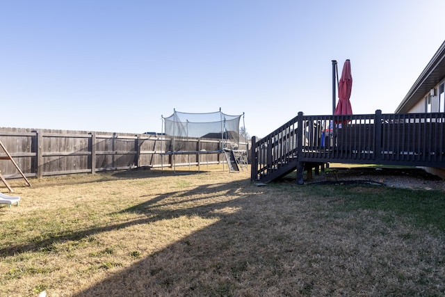 view of yard with a trampoline and a wooden deck