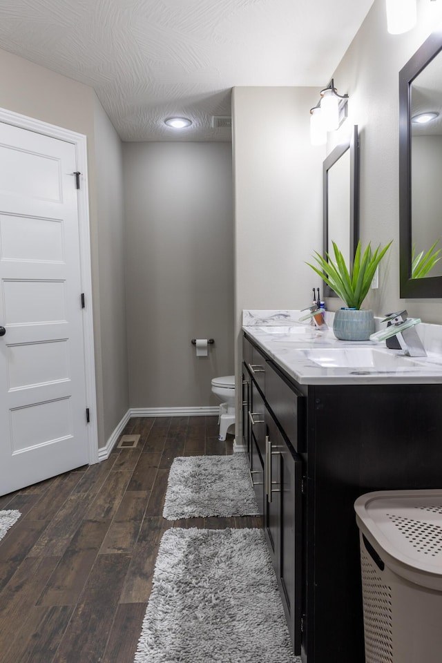 bathroom with toilet, vanity, and hardwood / wood-style flooring