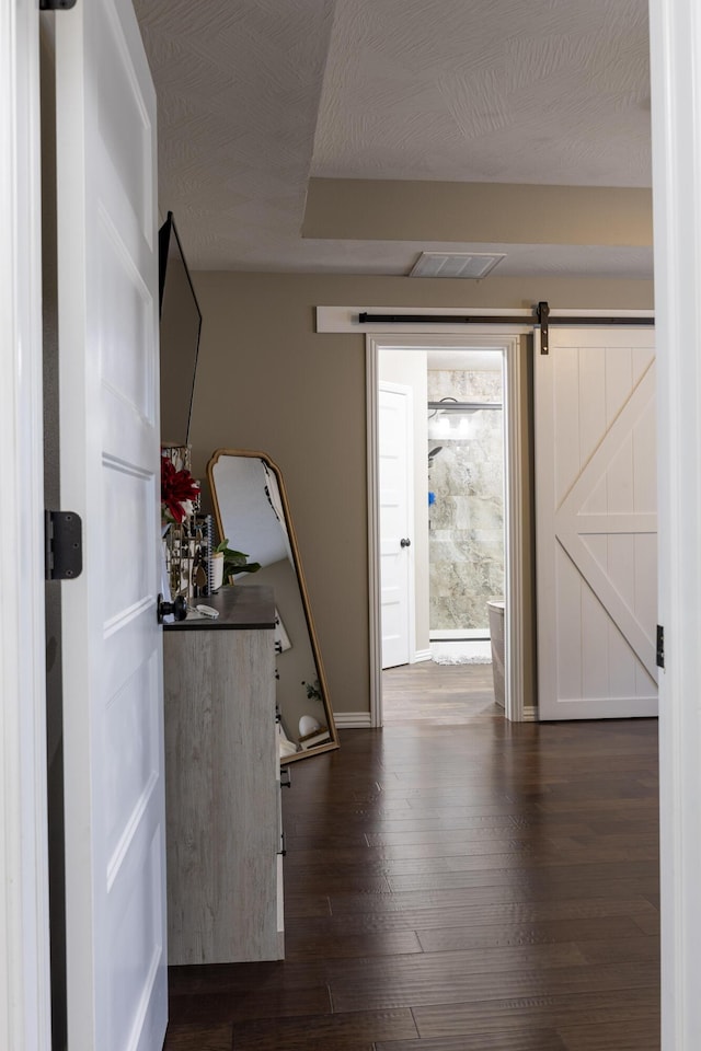 entryway featuring dark hardwood / wood-style floors, a barn door, and a textured ceiling