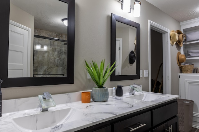 bathroom featuring vanity, a textured ceiling, and a shower with door