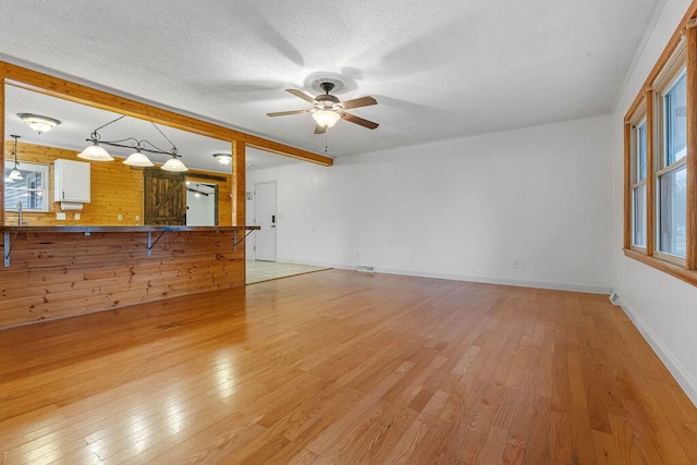 unfurnished living room featuring plenty of natural light, a textured ceiling, and light hardwood / wood-style flooring