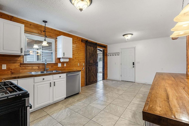 kitchen with hanging light fixtures, a barn door, wood walls, white cabinets, and appliances with stainless steel finishes