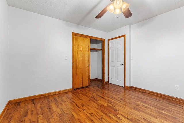 unfurnished bedroom with a closet, ceiling fan, hardwood / wood-style floors, and a textured ceiling