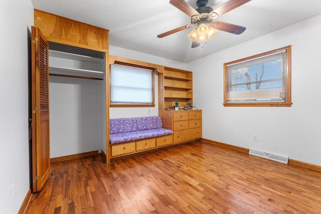 unfurnished bedroom featuring a textured ceiling, a closet, hardwood / wood-style flooring, and ceiling fan